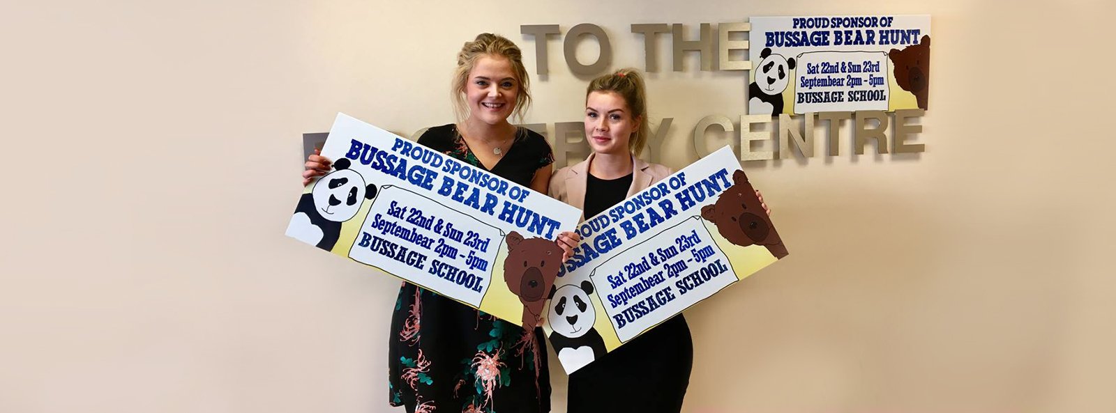 Jessica Pearce and Ellen Trueman, Sales Negotiators in The Property Centre's Stroud branch holding the Bussage Bear Hunt sold boards