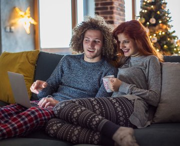 Couple at Christmas browsing the internet using their tablet